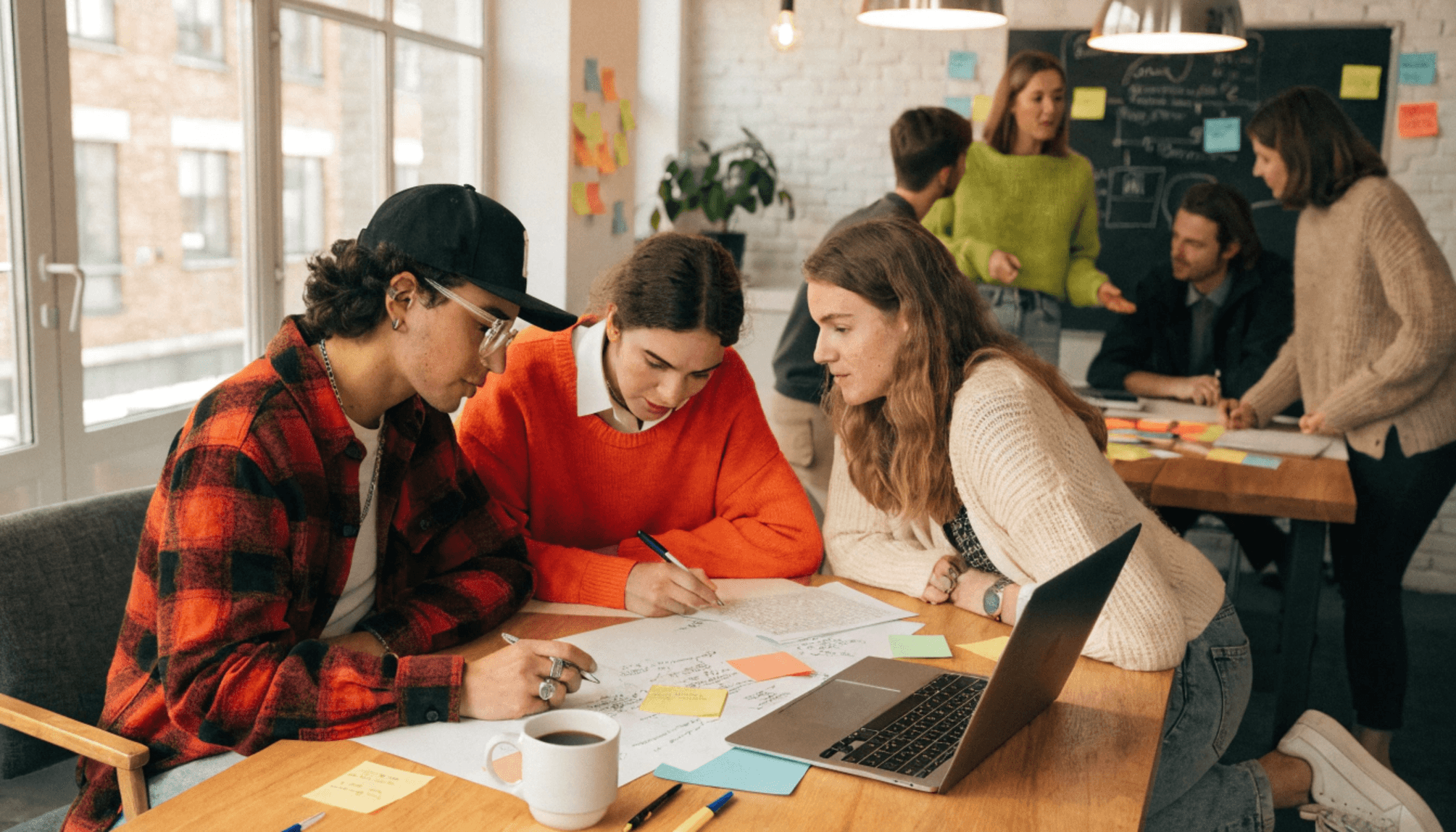 Young professionals collaborate around a table, reviewing documents and discussing ideas in a modern office.